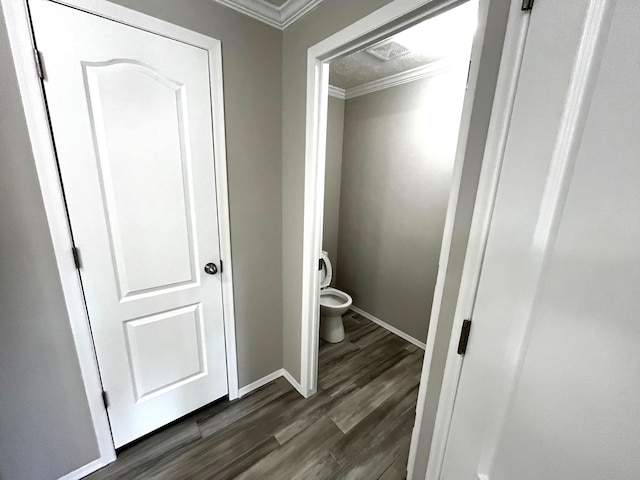 bathroom featuring toilet, wood finished floors, baseboards, and ornamental molding