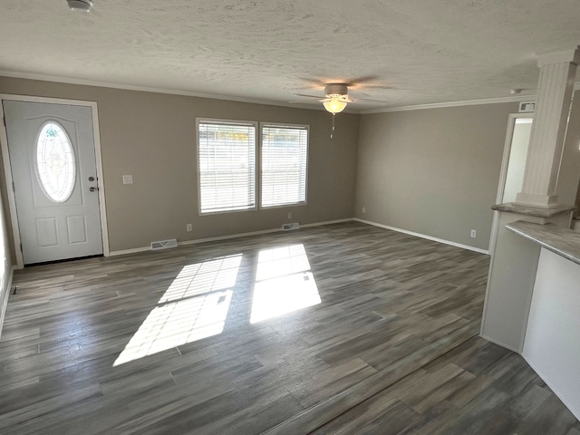 unfurnished living room with a wealth of natural light, visible vents, dark wood finished floors, and crown molding