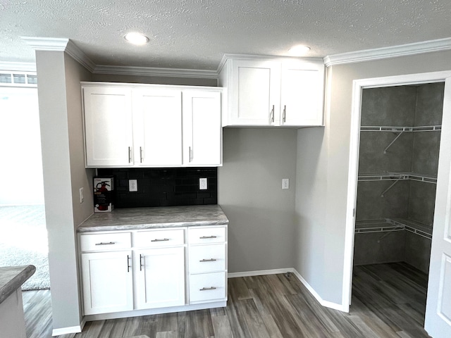 kitchen featuring white cabinetry, crown molding, and wood finished floors