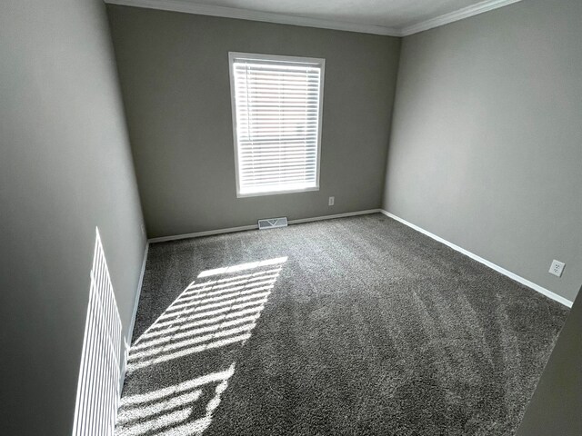 carpeted spare room featuring visible vents, baseboards, and ornamental molding