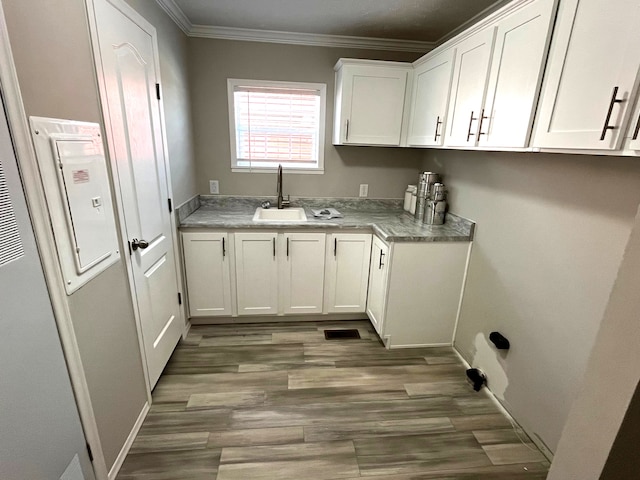 laundry room featuring crown molding, light wood-style floors, visible vents, and a sink