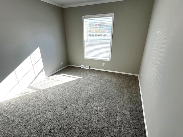 carpeted spare room featuring visible vents, baseboards, and crown molding