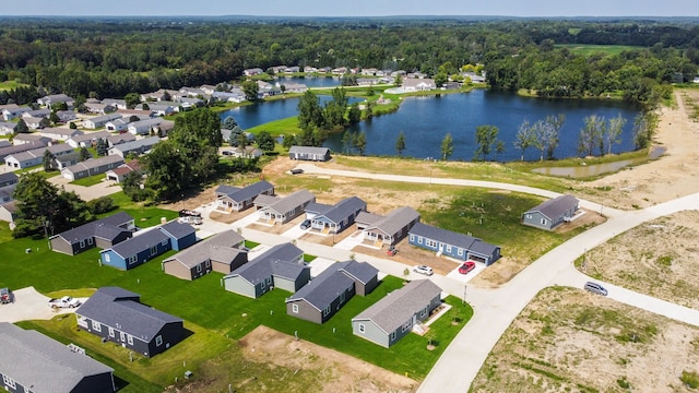 drone / aerial view featuring a residential view, a wooded view, and a water view