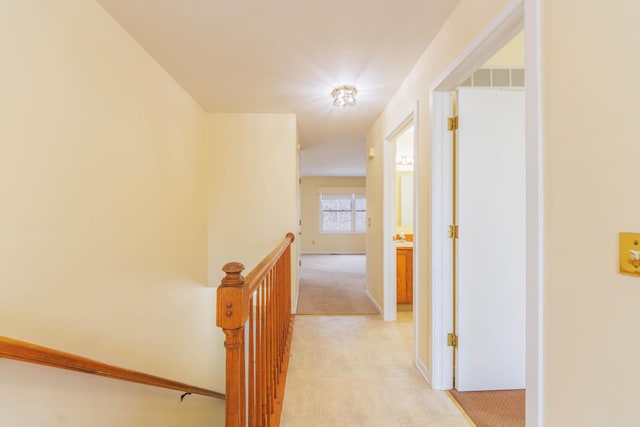 hall featuring light colored carpet and an upstairs landing