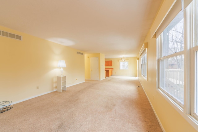 spare room featuring visible vents, light carpet, and baseboards