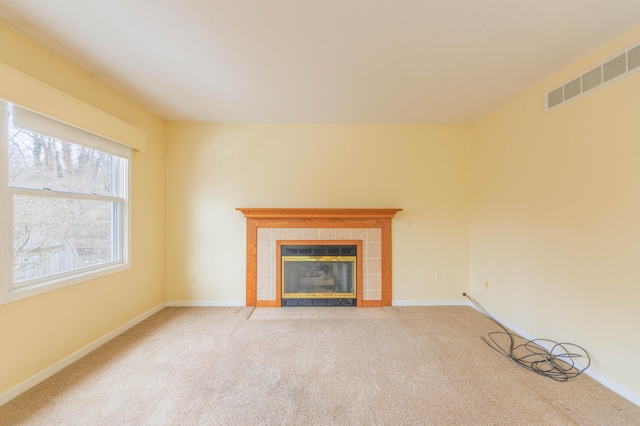 unfurnished living room featuring baseboards, visible vents, light colored carpet, and a tile fireplace