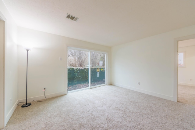 carpeted spare room featuring visible vents and baseboards