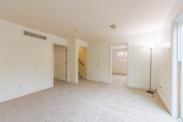 unfurnished room featuring visible vents, light carpet, baseboards, and stairs