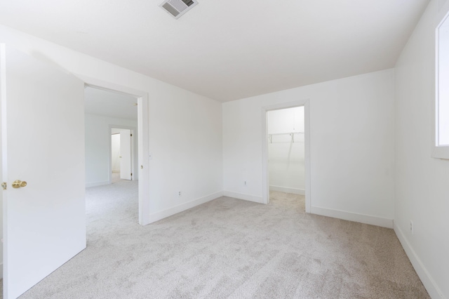 empty room featuring light carpet, visible vents, and baseboards