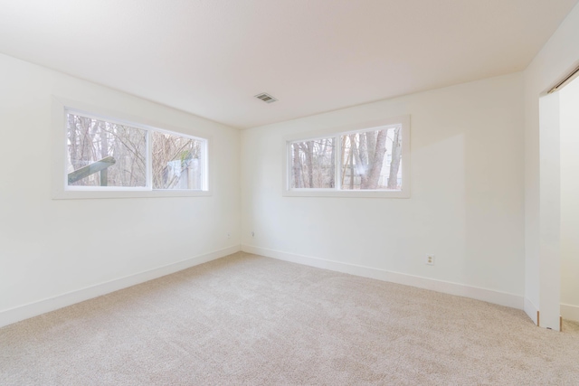 carpeted spare room with visible vents and baseboards