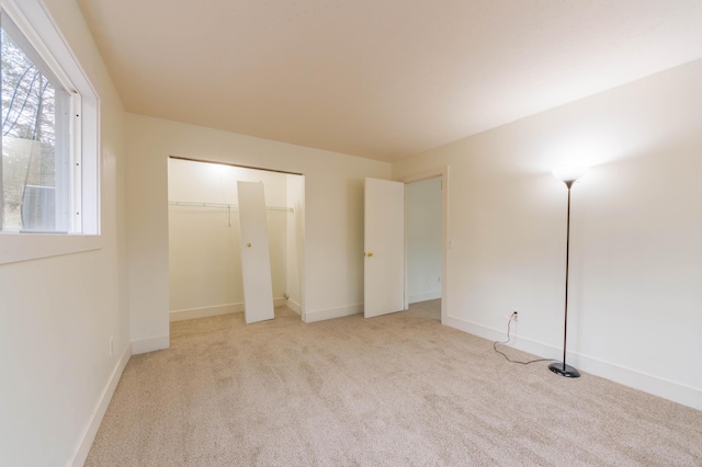 unfurnished bedroom featuring a closet, light colored carpet, and baseboards