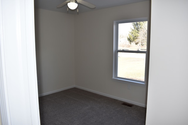 unfurnished room with a ceiling fan, dark carpet, visible vents, and baseboards
