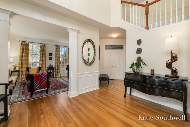 foyer entrance with a wainscoted wall, decorative columns, a decorative wall, and wood finished floors