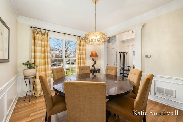 dining area with ornamental molding, wood finished floors, visible vents, and ornate columns