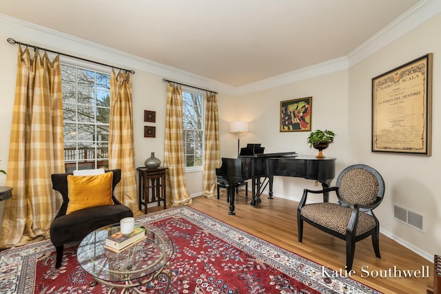 living area with visible vents, crown molding, baseboards, and wood finished floors