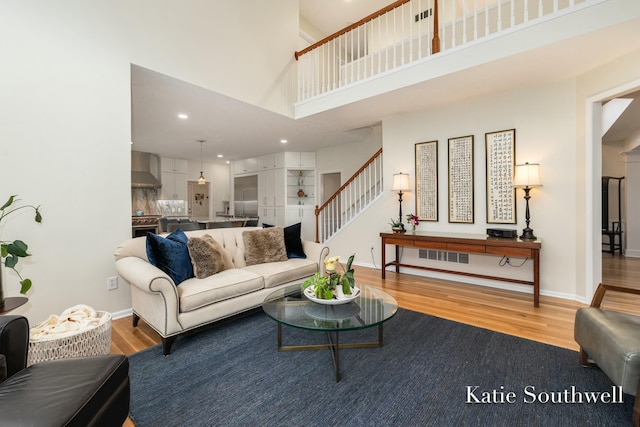 living room featuring stairway, recessed lighting, wood finished floors, and baseboards