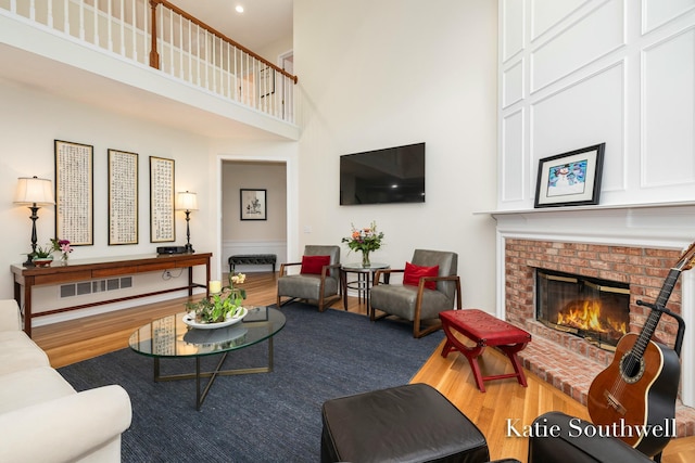 living area featuring a fireplace, wood finished floors, and a towering ceiling