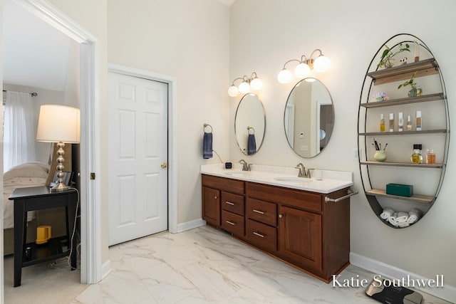 full bathroom with double vanity, marble finish floor, baseboards, and a sink