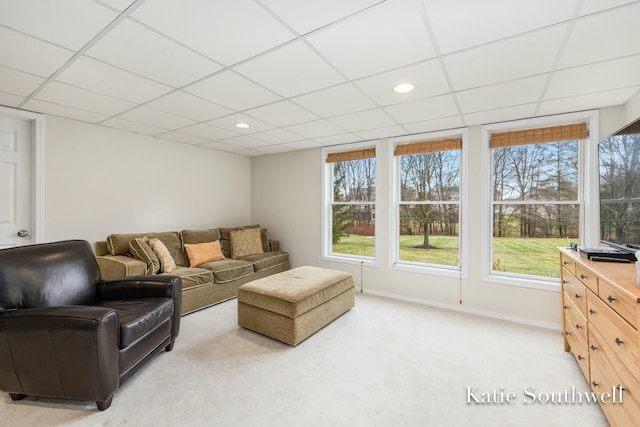 living room featuring baseboards, a drop ceiling, recessed lighting, and light colored carpet