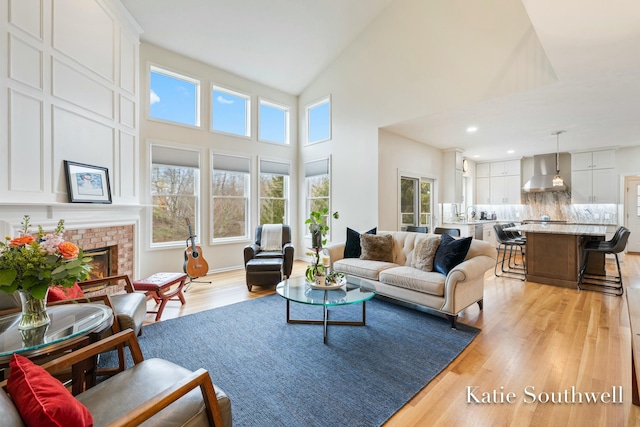 living room featuring high vaulted ceiling, recessed lighting, a fireplace, and light wood-style floors