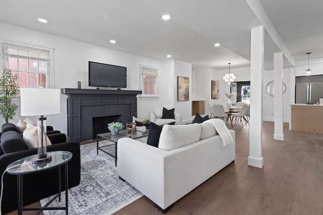 living area featuring a healthy amount of sunlight, a brick fireplace, dark wood-style flooring, and recessed lighting