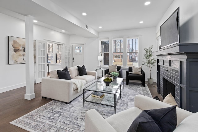 living room featuring a fireplace, recessed lighting, visible vents, wood finished floors, and baseboards