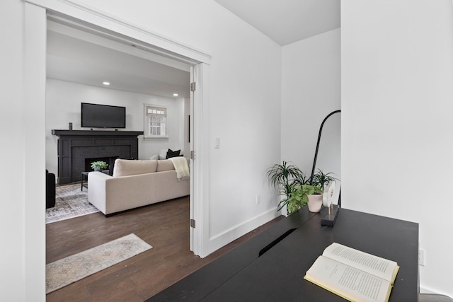 interior space featuring recessed lighting, a fireplace, baseboards, and wood finished floors