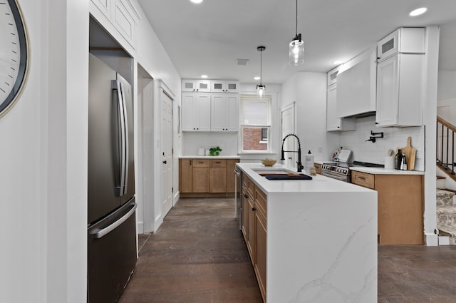 kitchen featuring a center island with sink, custom exhaust hood, backsplash, appliances with stainless steel finishes, and a sink