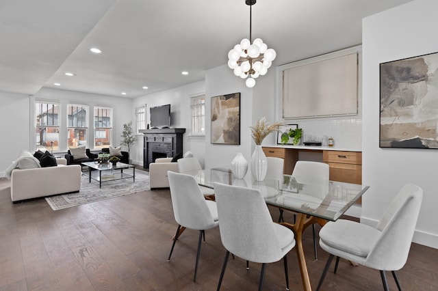 dining room featuring a notable chandelier, recessed lighting, dark wood-type flooring, a fireplace, and baseboards