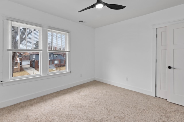 spare room featuring carpet, visible vents, ceiling fan, and baseboards