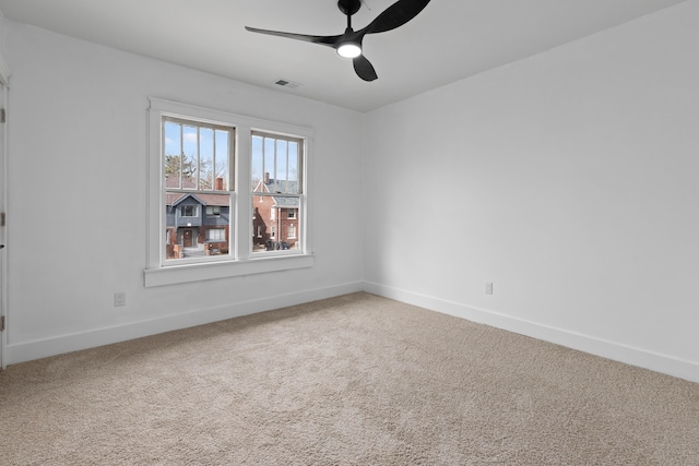 empty room with a ceiling fan, carpet flooring, visible vents, and baseboards