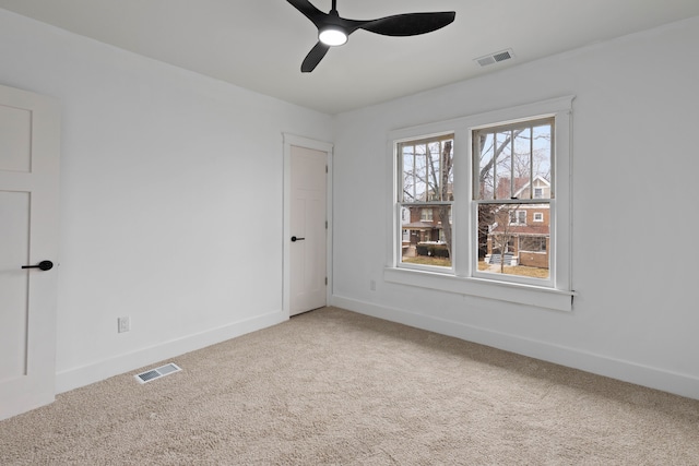 carpeted spare room with visible vents, ceiling fan, and baseboards