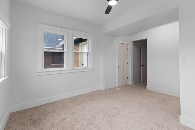 carpeted empty room featuring a ceiling fan and baseboards