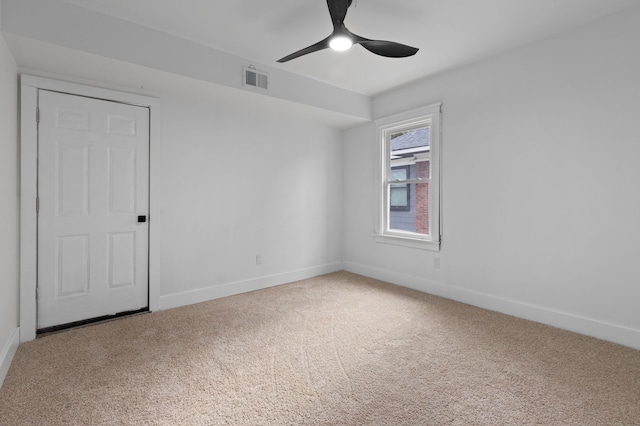 carpeted spare room with a ceiling fan, visible vents, and baseboards