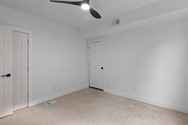 carpeted spare room with baseboards, visible vents, and a ceiling fan