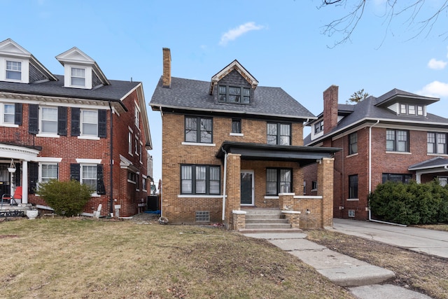 traditional style home featuring covered porch, a shingled roof, a front yard, and brick siding