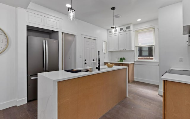 kitchen with dark wood finished floors, glass insert cabinets, freestanding refrigerator, light countertops, and white cabinetry