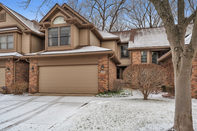 view of front facade featuring brick siding, driveway, an attached garage, and roof with shingles