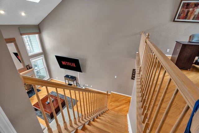 stairway featuring a towering ceiling, baseboards, and wood finished floors