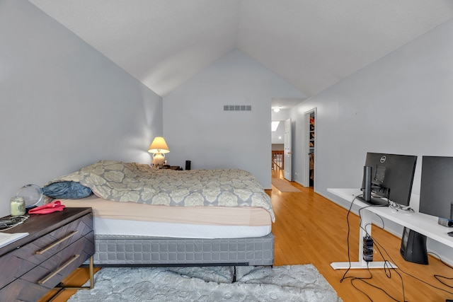 bedroom featuring vaulted ceiling, wood finished floors, and visible vents