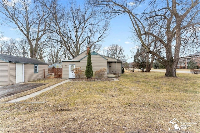 view of side of property with an outbuilding, a chimney, and a lawn