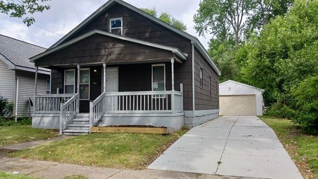 bungalow featuring a porch, an outbuilding, and a garage