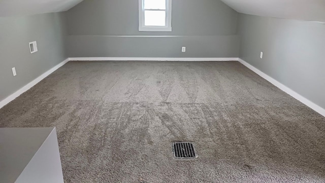 additional living space with vaulted ceiling, carpet, visible vents, and baseboards