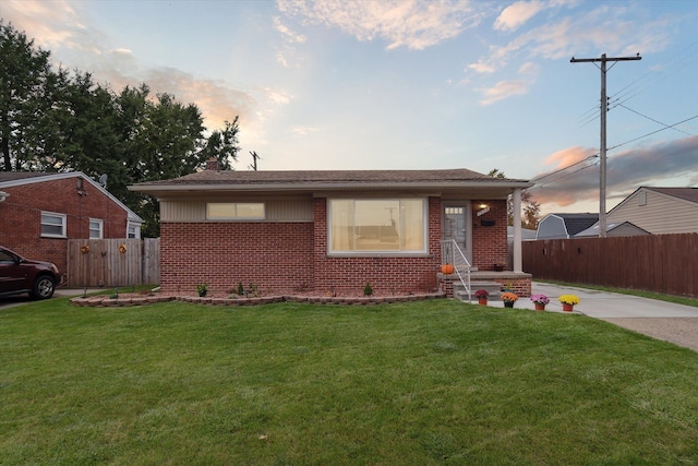 view of front facade with brick siding, a front yard, and fence