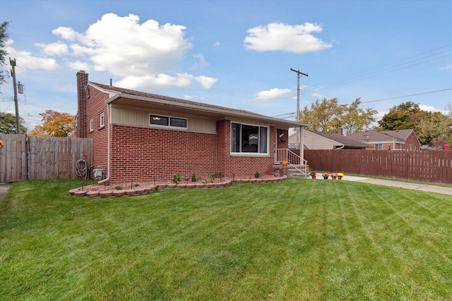 view of front facade with a front yard, brick siding, a chimney, and fence