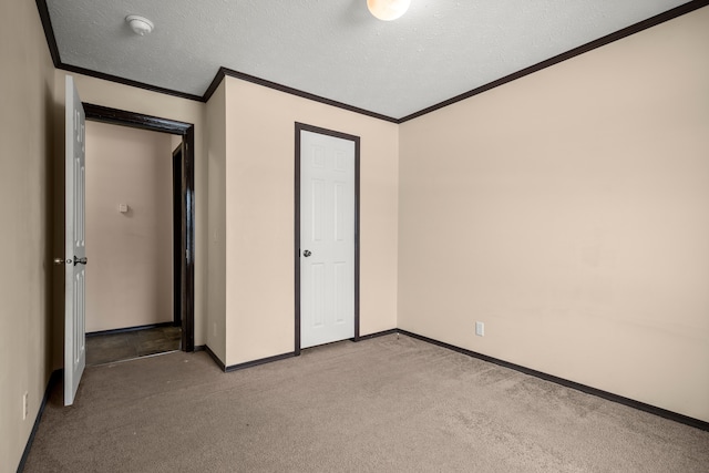 unfurnished bedroom featuring carpet, a textured ceiling, baseboards, and crown molding