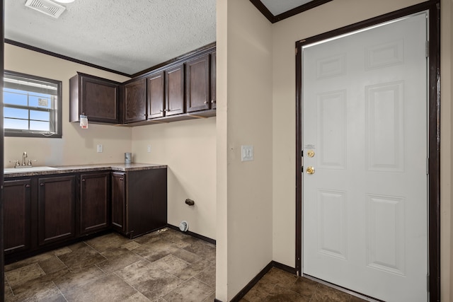 clothes washing area featuring baseboards, visible vents, crown molding, a textured ceiling, and a sink