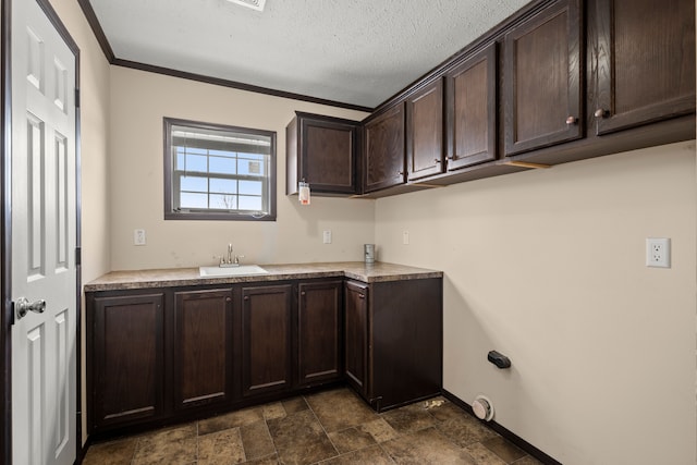 laundry area with baseboards, stone finish flooring, crown molding, a textured ceiling, and a sink