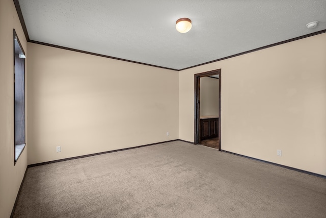 carpeted empty room with ornamental molding, a textured ceiling, and baseboards