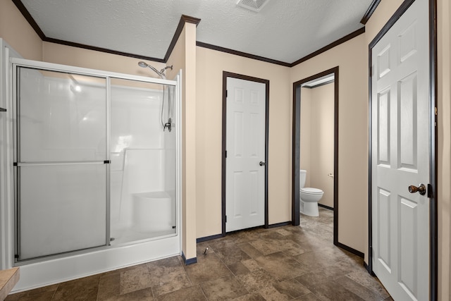 bathroom featuring crown molding, a shower stall, toilet, and a textured ceiling